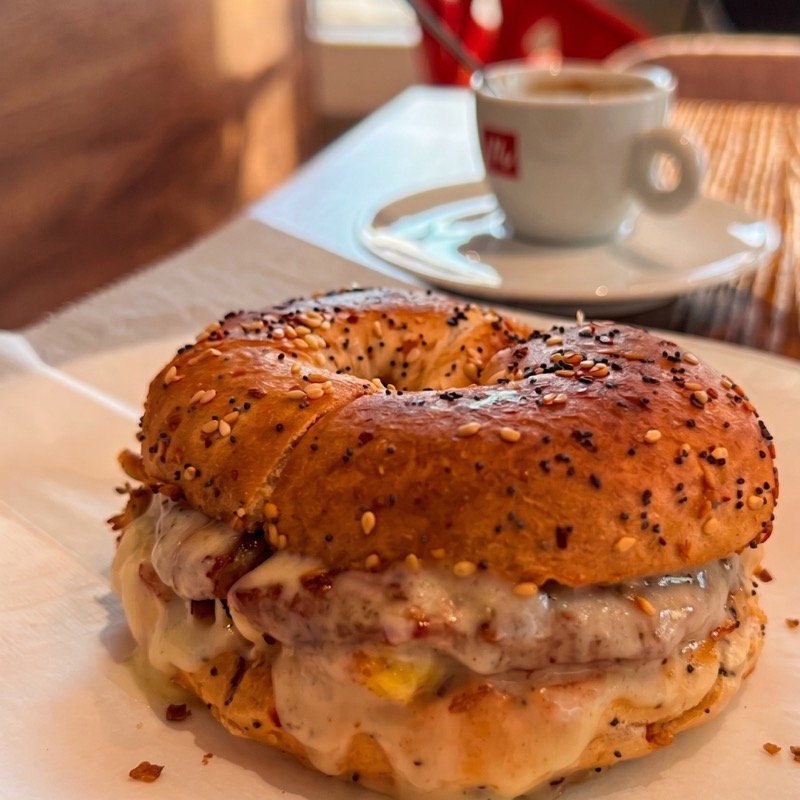 A breakfast bagel sandwich with an espresso